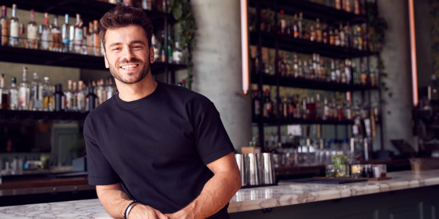 Portrait Of Confident Male Owner Of Restaurant Bar Leaning Against Counter