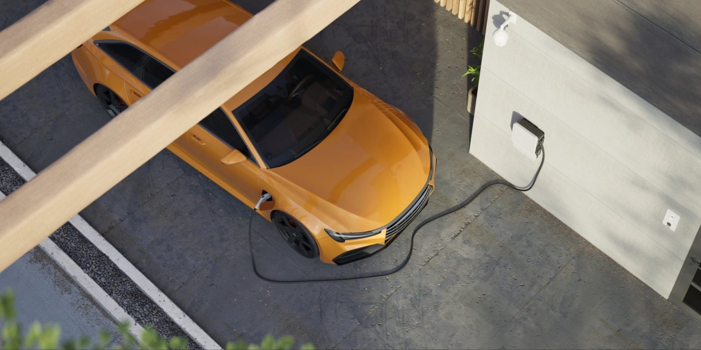 High angle Generic electric vehicle EV hybrid car is being charged from a wallbox on a contemporary modern residential building house
