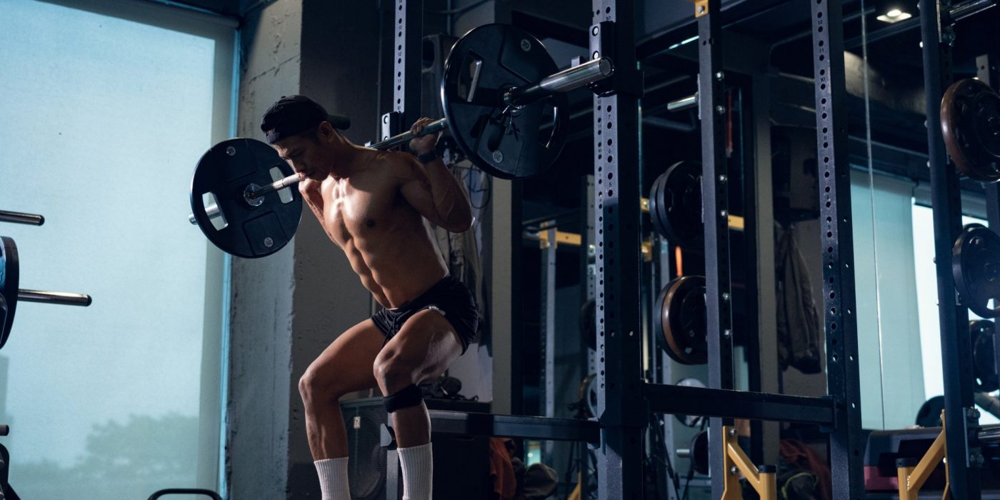 Sporty man bodybuilder or powerlifter exercising deadlift with barbell on cross training in a gym. Fitness exercising in gym.