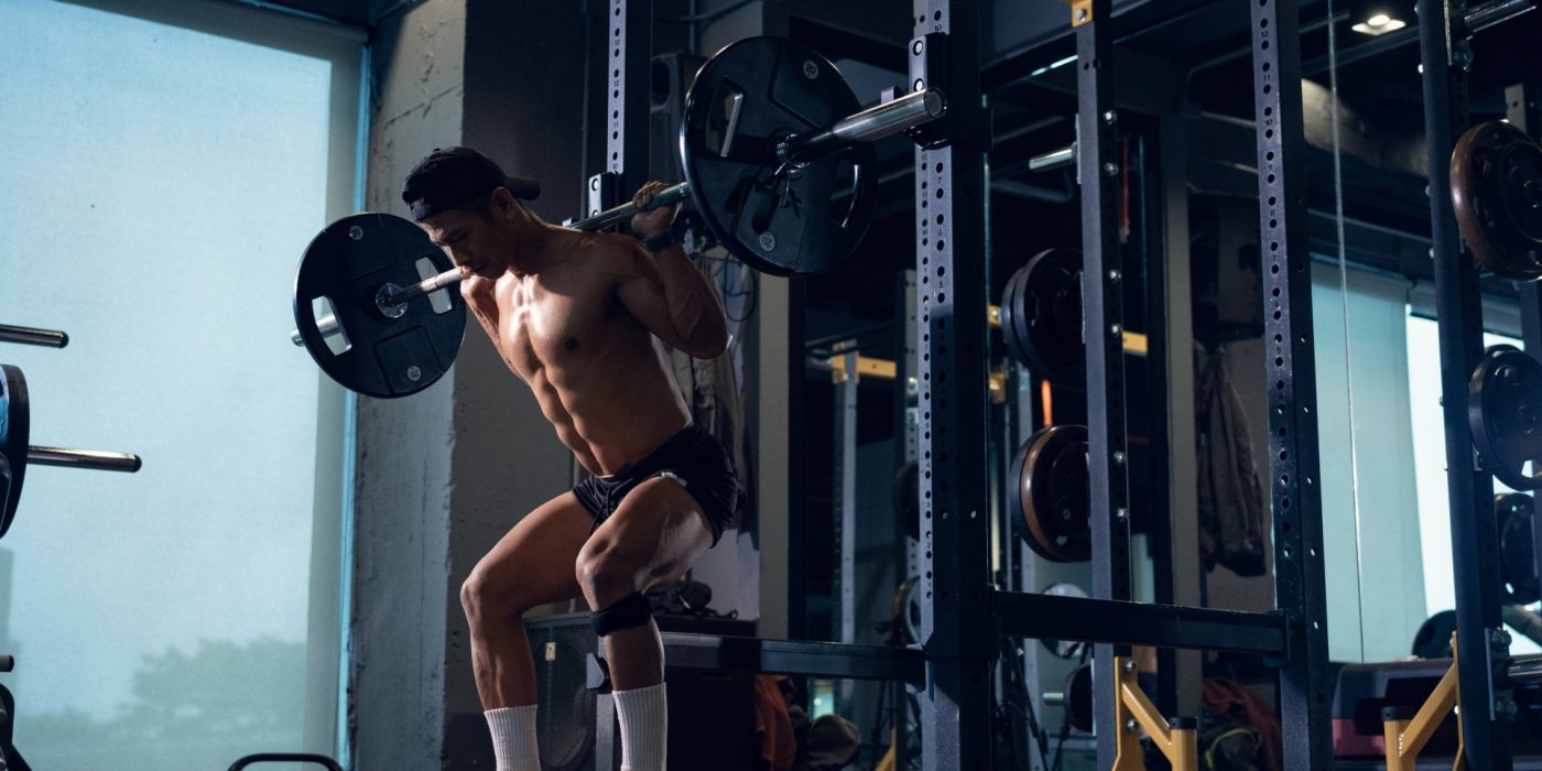 Sporty man bodybuilder or powerlifter exercising deadlift with barbell on cross training in a gym. Fitness exercising in gym.