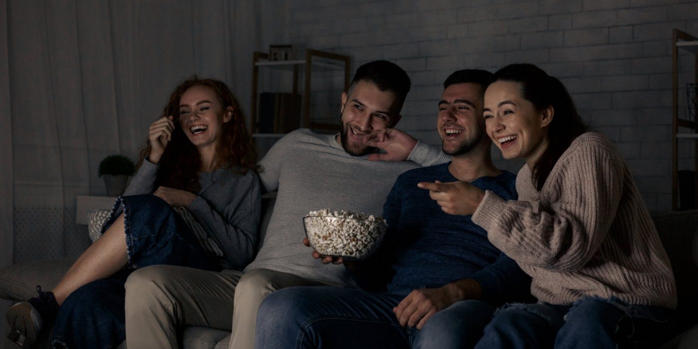 Happy friends watching comedy film and laughing, relaxing at home together
