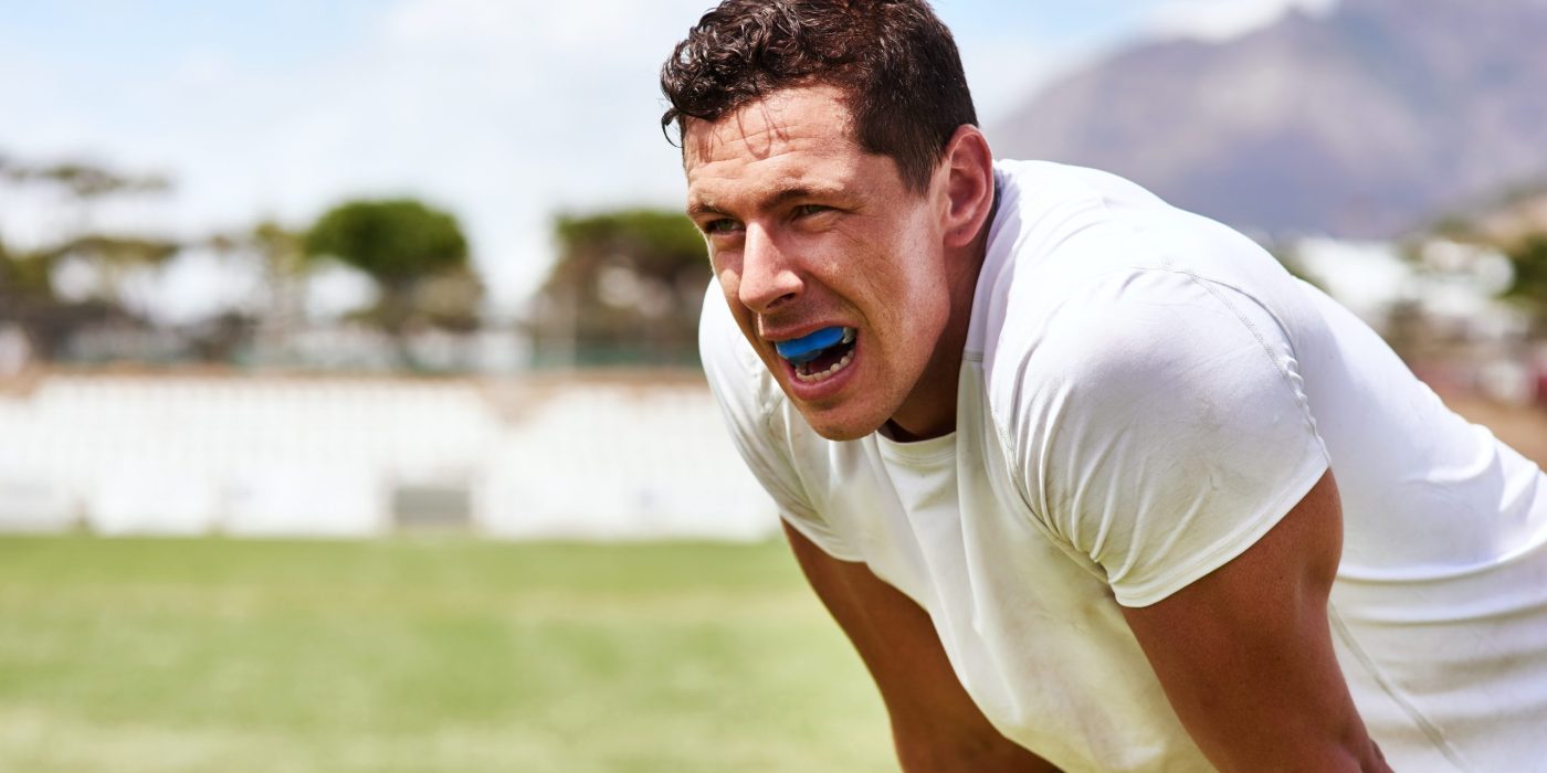 Male athlete wearing a protective mouthguard while playing contact sport with adult braces, metal braces or ceramic braces.